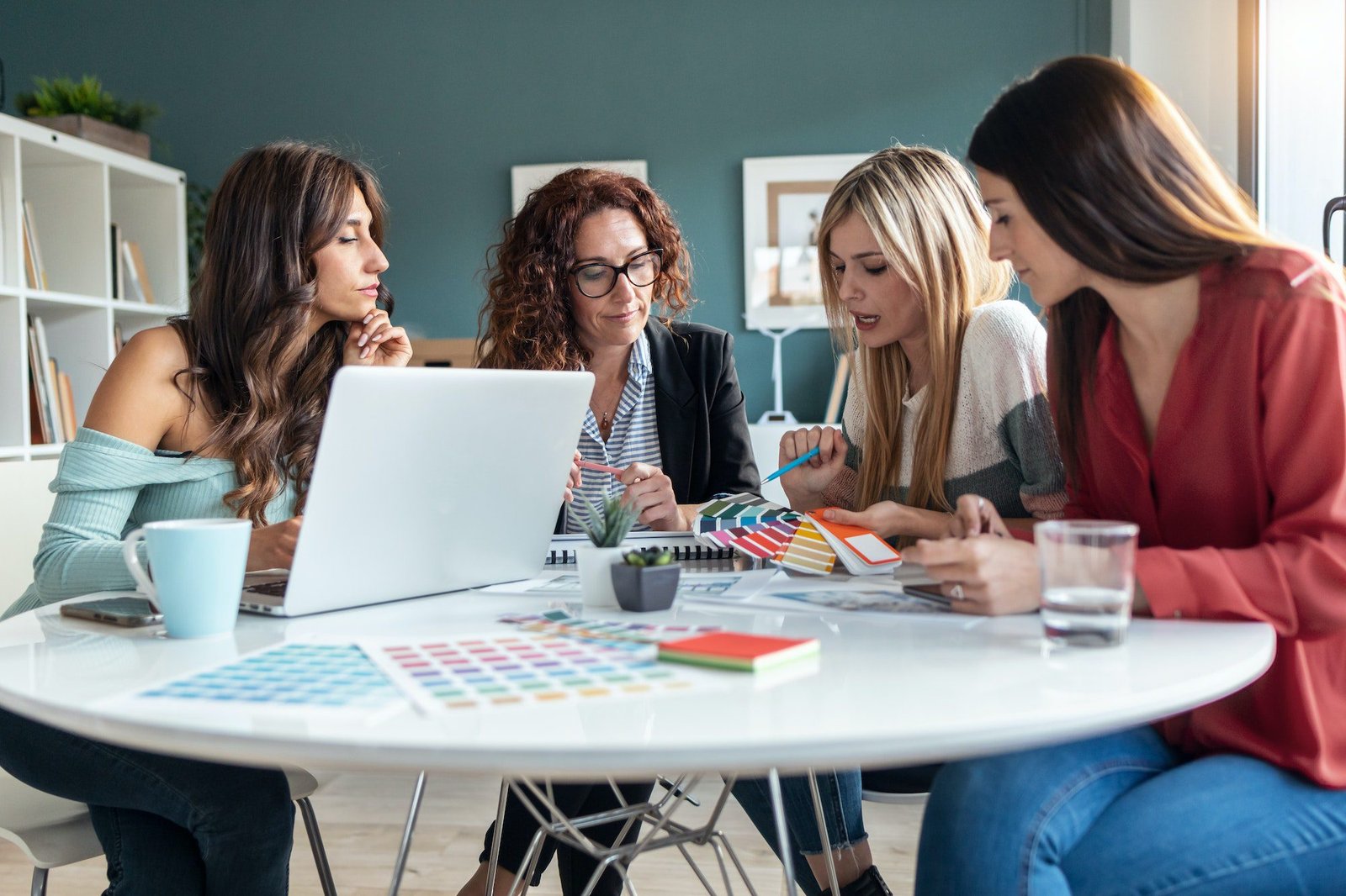 Group of multiage designer women working in a design project while choosing materials in the office.